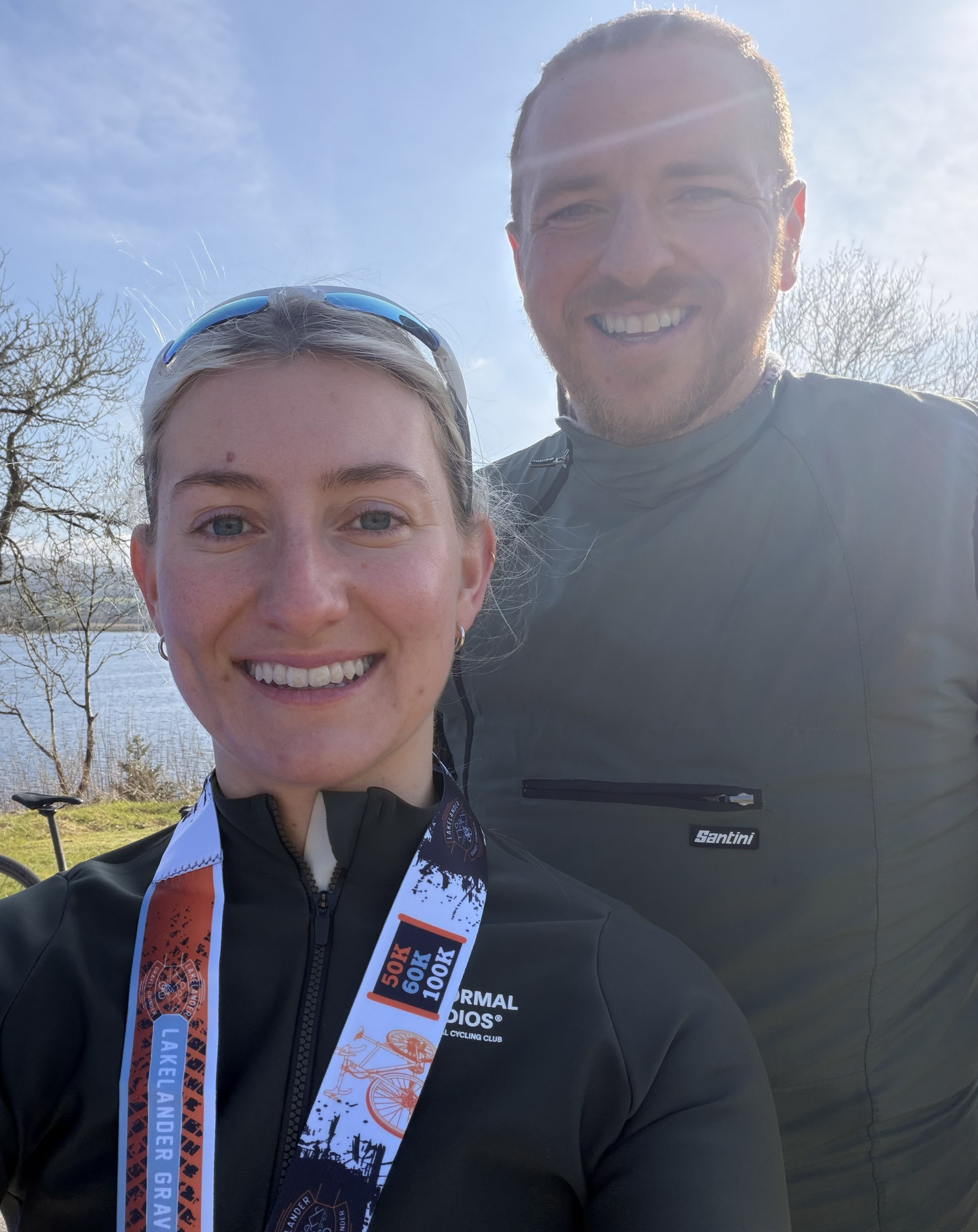 Two TOZA riders smiling outdoors beside the water after a ride.